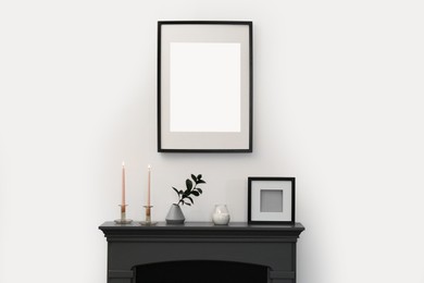 Photo of Fireplace, decorative elements and photo frames in room with light wall. Interior design