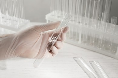 Photo of Scientist holding empty test tube at white table, closeup