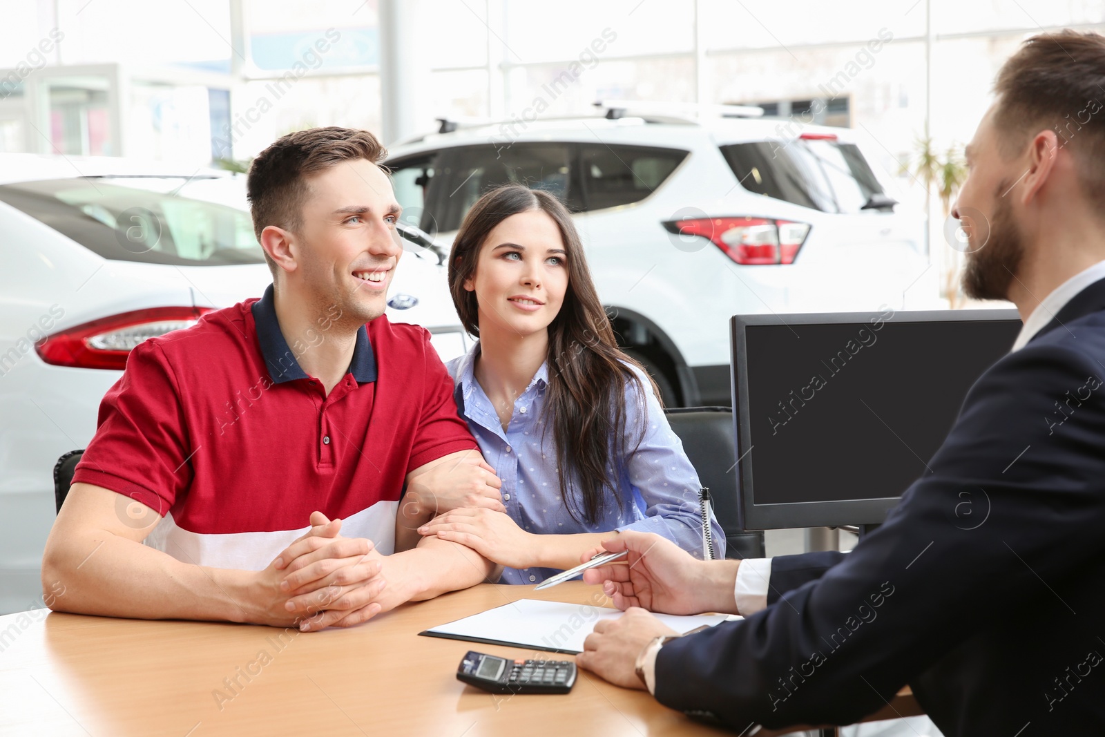 Photo of Young couple buying new car at dealership