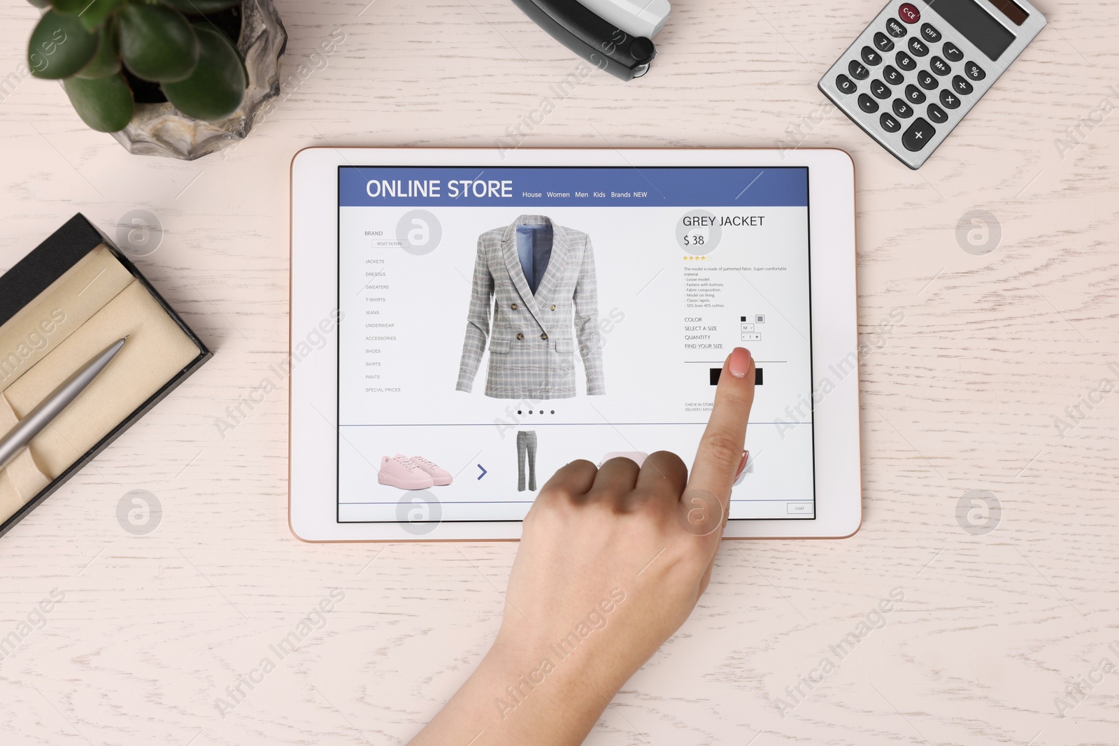 Photo of Woman with tablet shopping online at white wooden table, top view