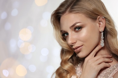 Photo of Beautiful young woman with elegant jewelry against defocused lights. Space for text