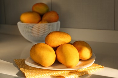 Delicious ripe mangos on white table indoors
