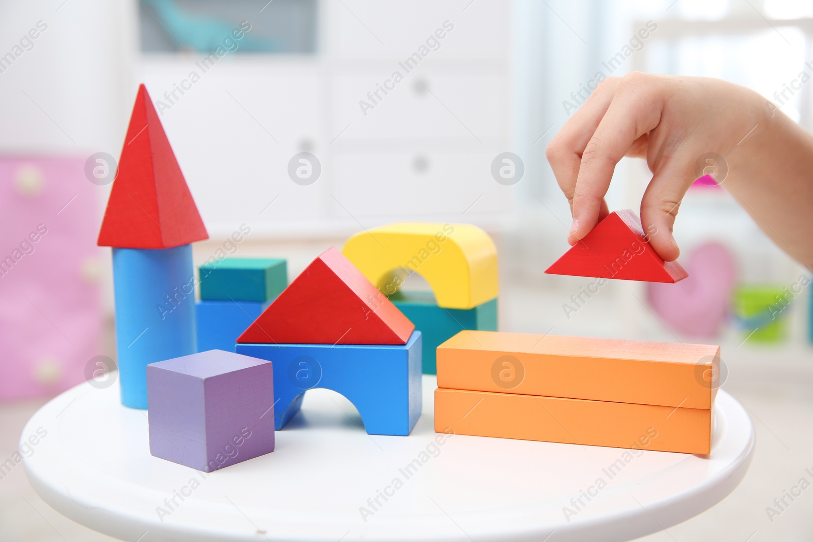 Photo of Cute child playing with colorful blocks at home, closeup