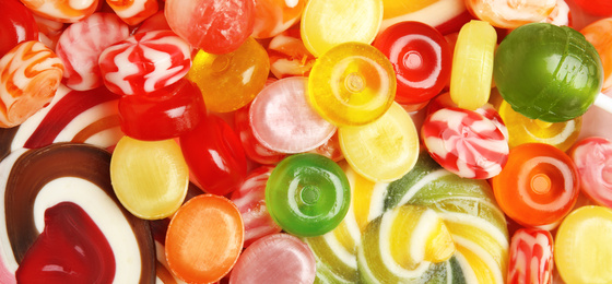 Different delicious colorful candies as background, top view. Banner design 