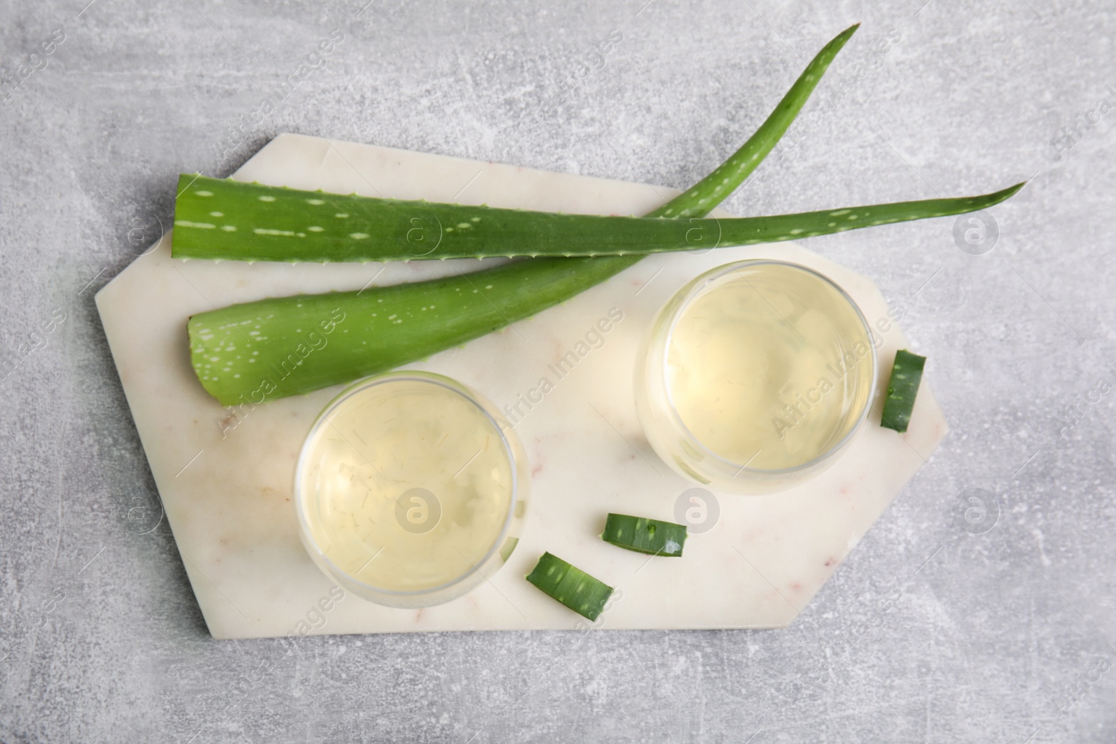 Photo of Fresh aloe drink in glasses and leaves on light grey table, flat lay