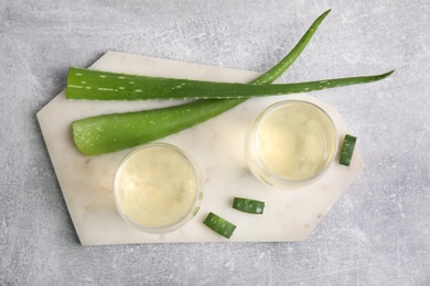 Photo of Fresh aloe drink in glasses and leaves on light grey table, flat lay