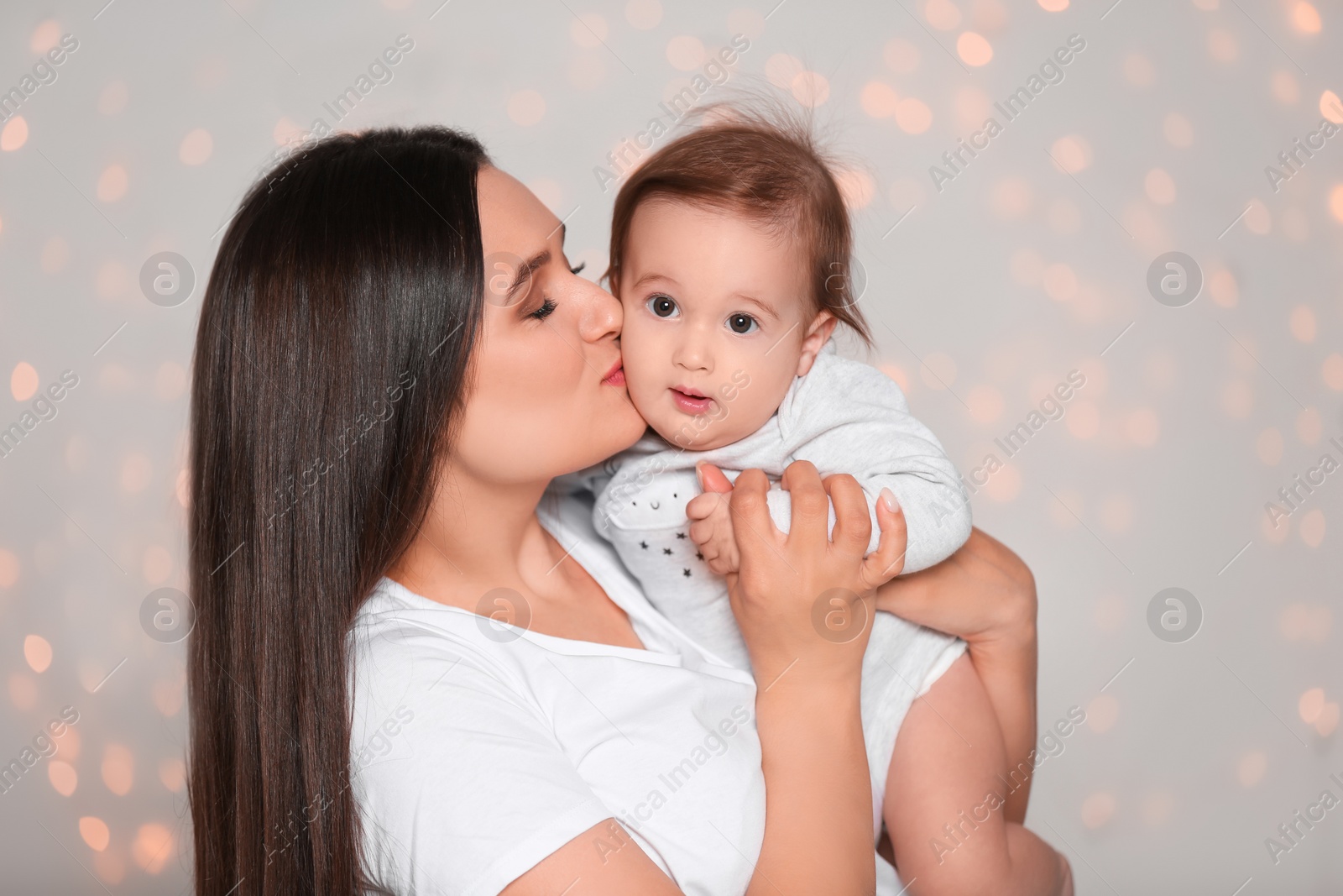 Photo of Portrait of young mother and her adorable baby against defocused lights