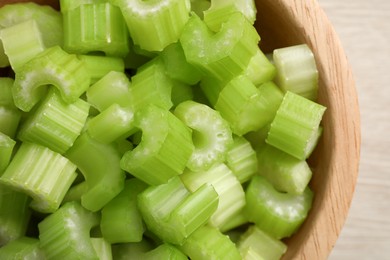 Photo of Fresh cut celery stalks in bowl on wooden table, top view
