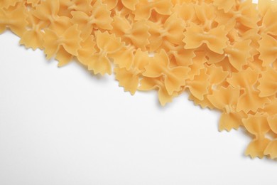 Photo of Raw farfalle pasta on white background, top view. Space for text