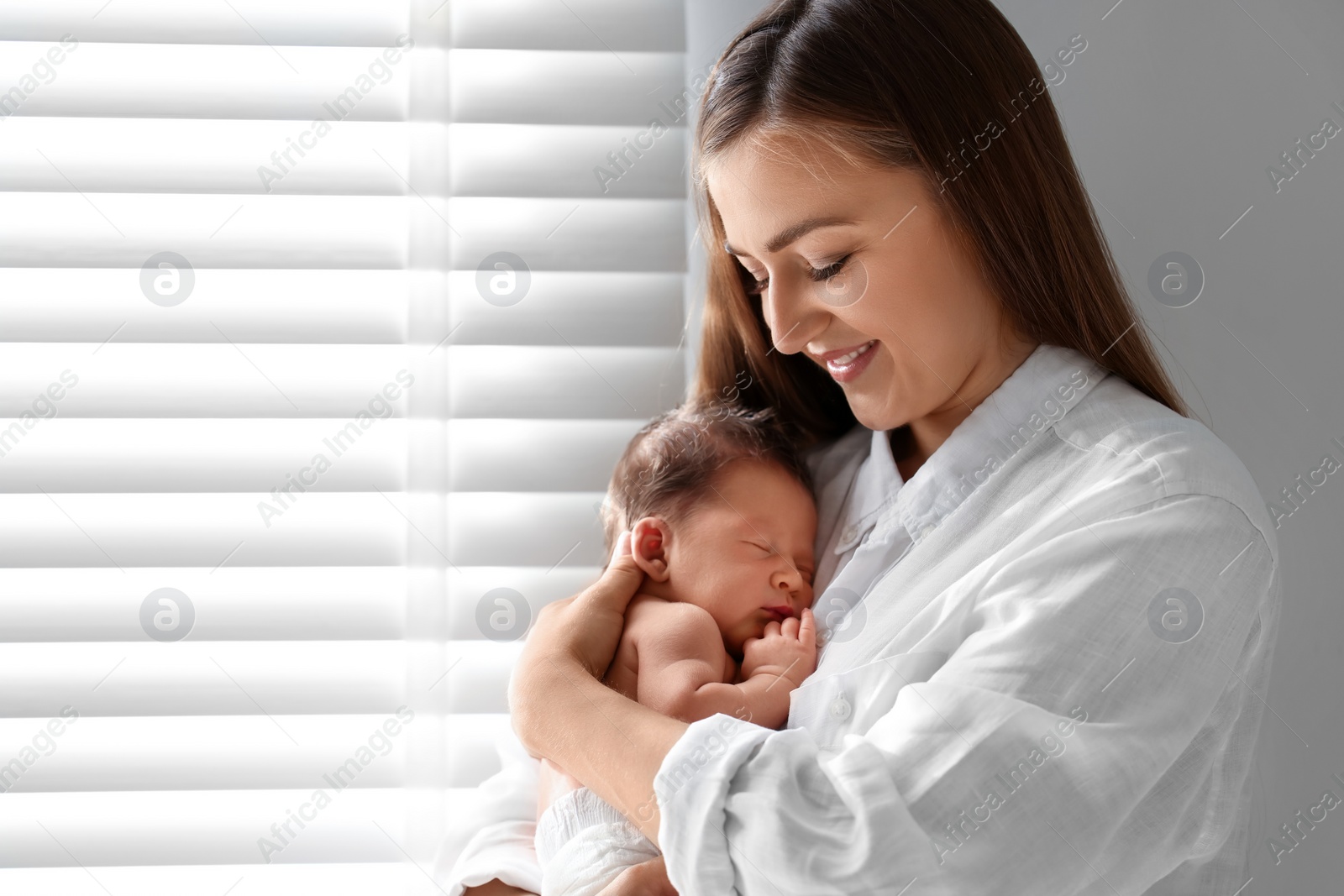 Photo of Mother holding her cute newborn baby indoors. Space for text
