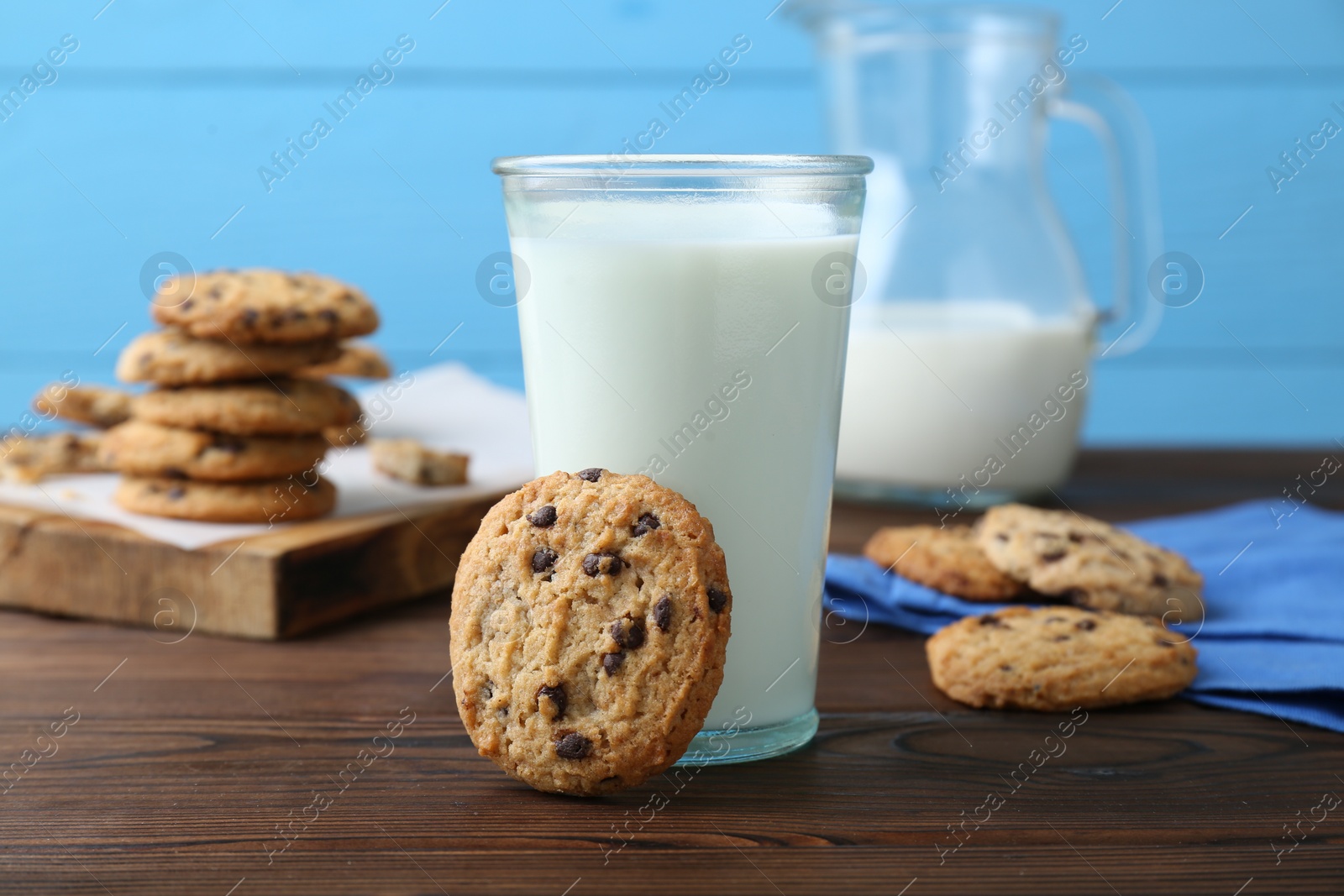 Delicious chocolate chip cookies and glass of milk on wooden table Photo of Delicious chocolate chip cookies and glass of milk on wooden table