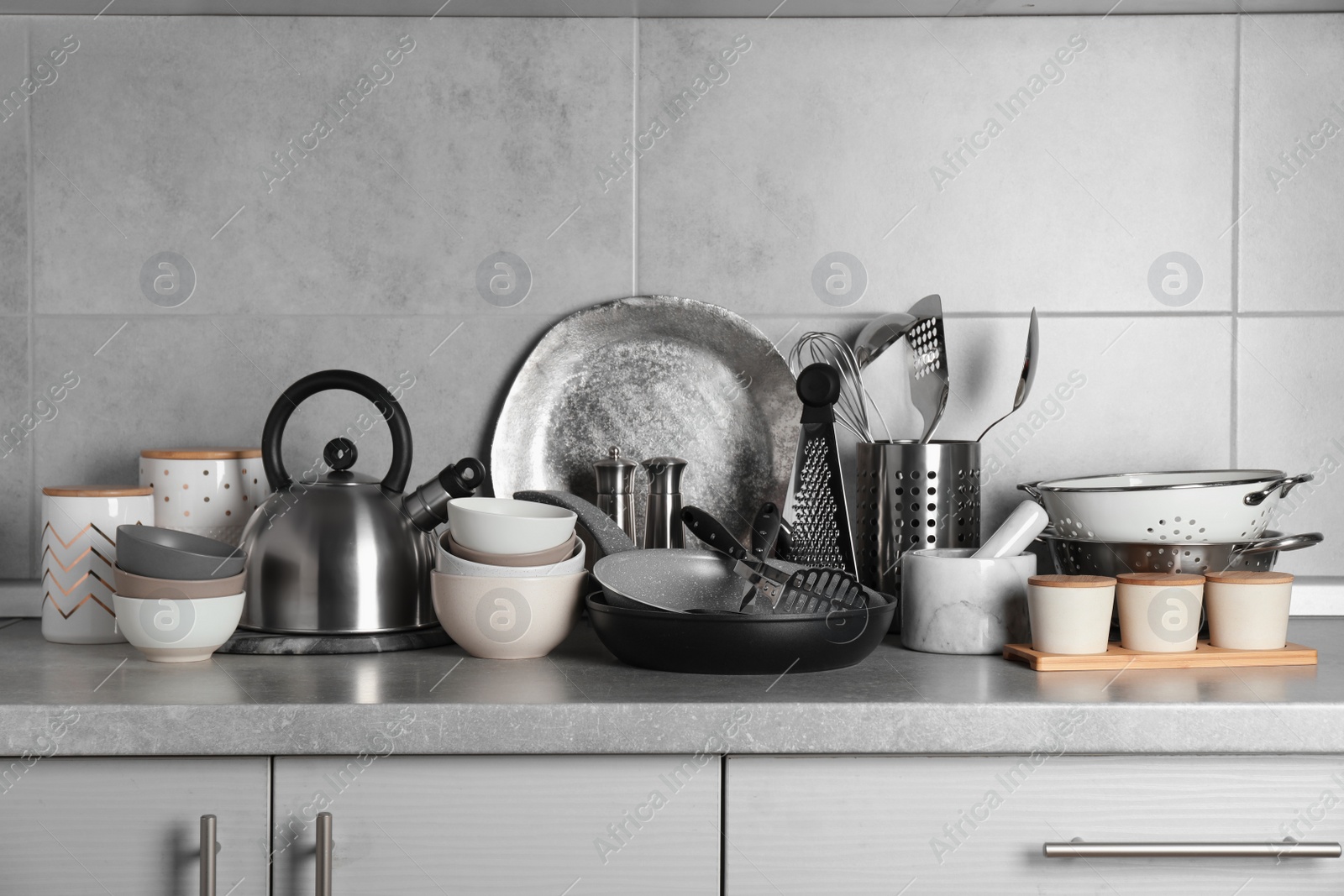 Photo of Set of different cooking utensils on grey countertop in kitchen