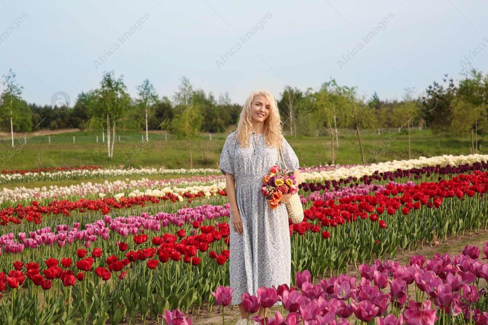 Photo of Woman with bag of spring flowers in beautiful tulip field