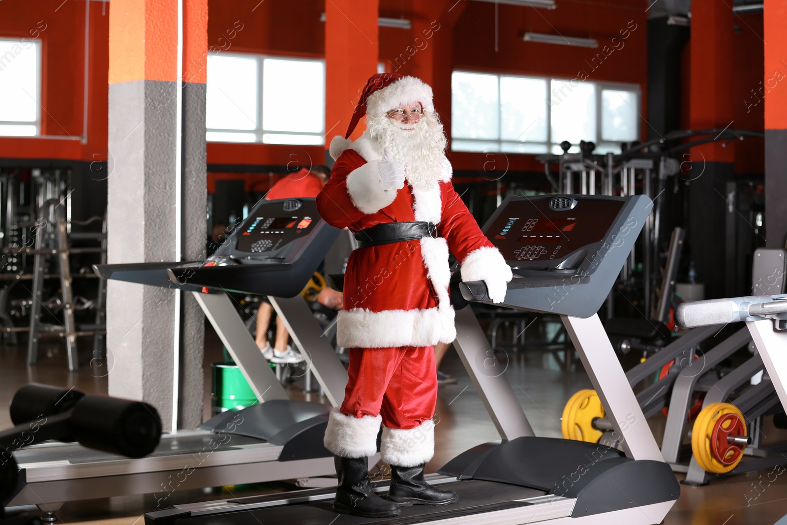 Photo of Authentic Santa Claus training on treadmill in modern gym