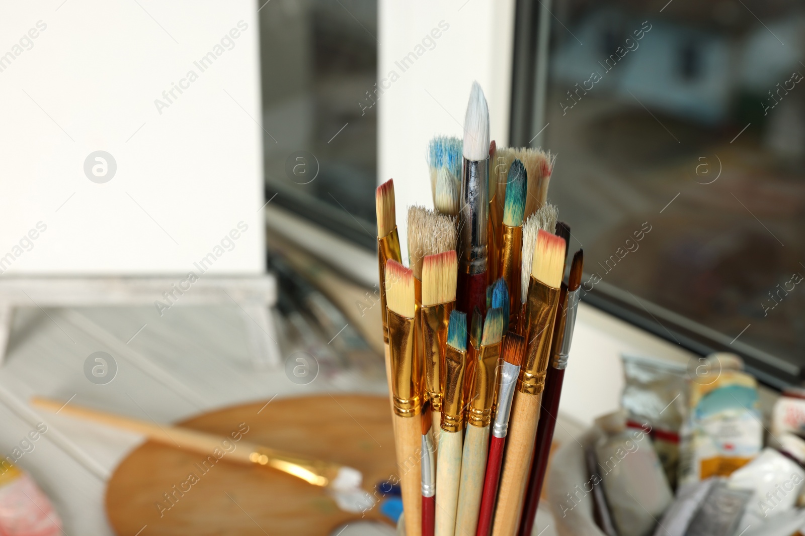 Photo of Many different paintbrushes near window, closeup view