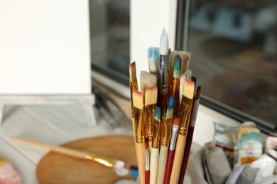 Photo of Many different paintbrushes near window, closeup view