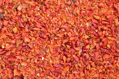 Photo of Aromatic spice. Red chili pepper flakes as background, top view