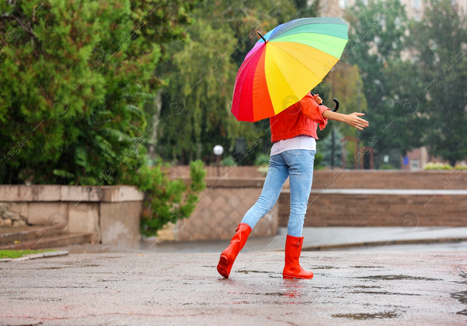 Photo of Young woman with bright umbrella under rain outdoors