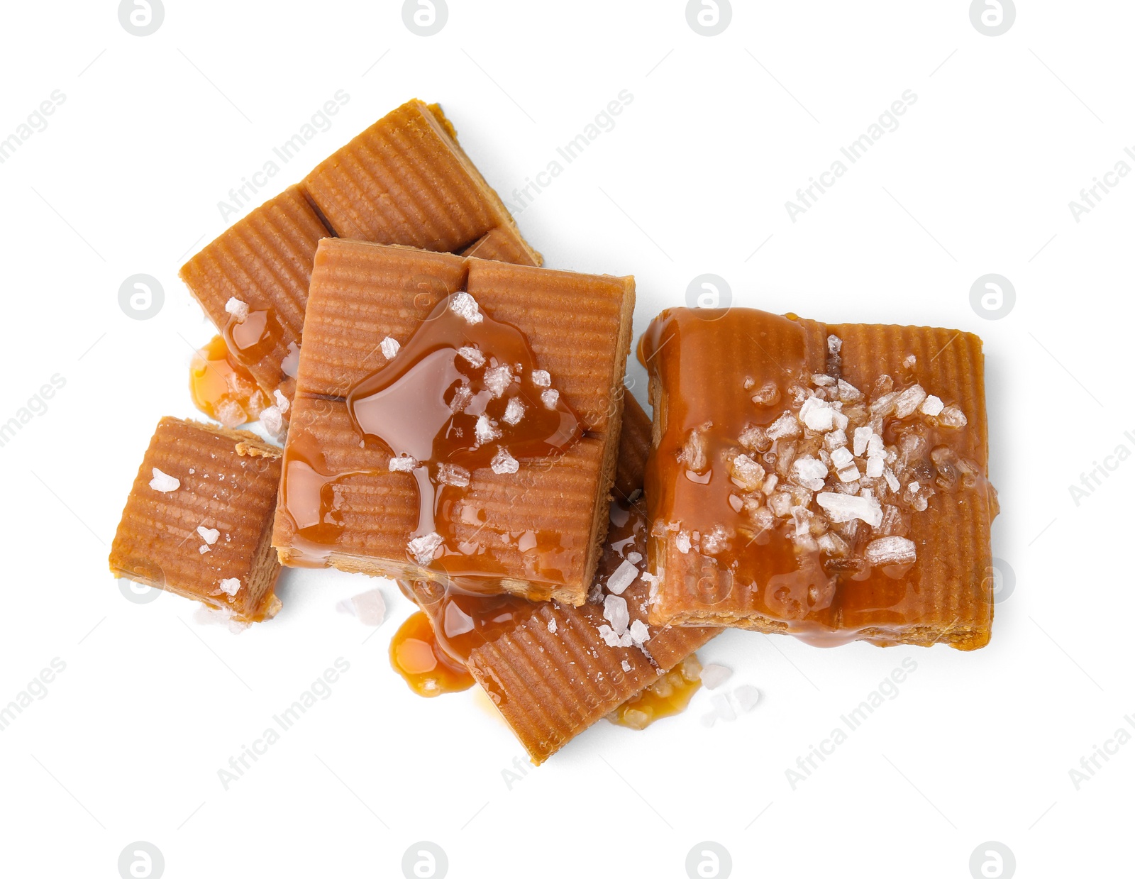 Photo of Yummy caramel candies and sea salt isolated on white, top view