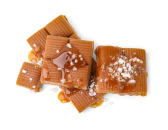 Yummy caramel candies and sea salt isolated on white, top view