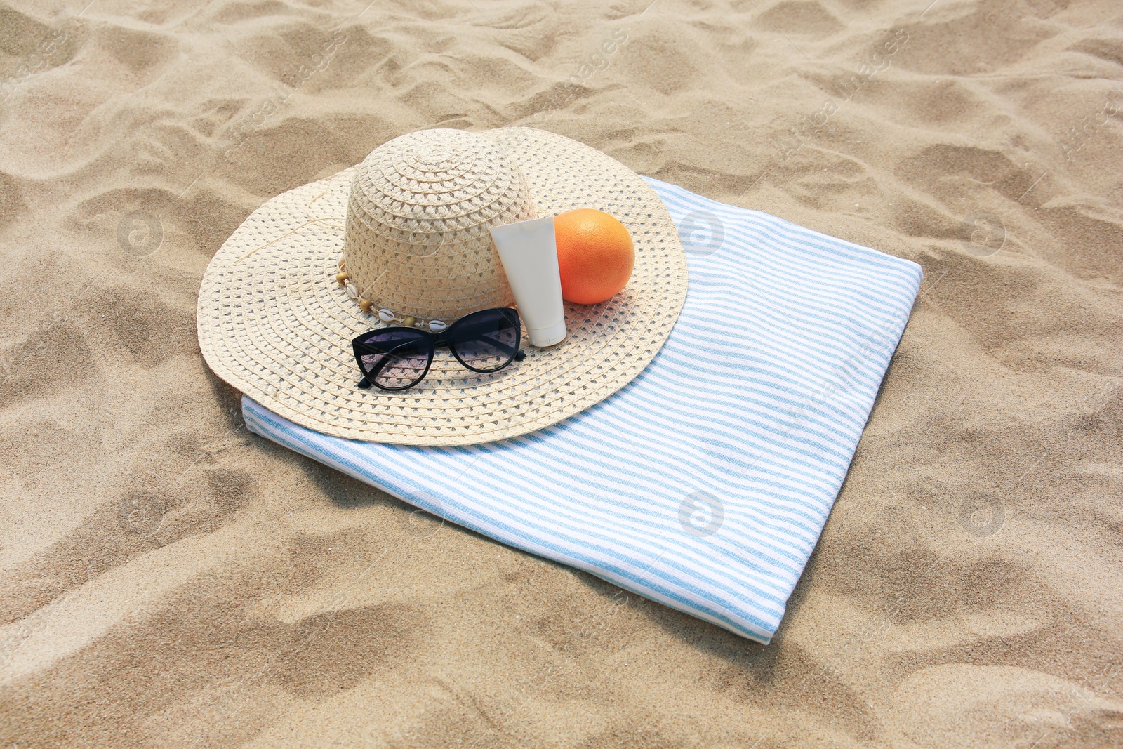 Photo of Beach accessories and orange on sand, above view