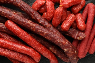 Photo of Many thin dry smoked sausages on table, top view