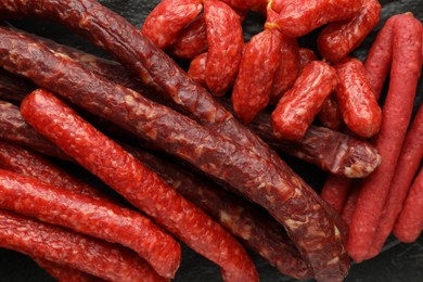 Many thin dry smoked sausages on table, top view