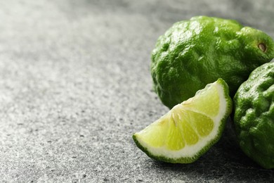 Photo of Whole and cut ripe bergamot fruits on grey table, closeup. Space for text