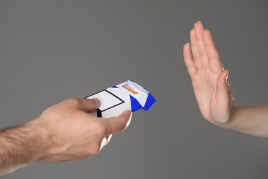 Photo of Stop smoking concept. Woman refusing cigarettes on gray background, closeup