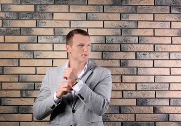 Photo of Handsome young man in suit near brick wall background