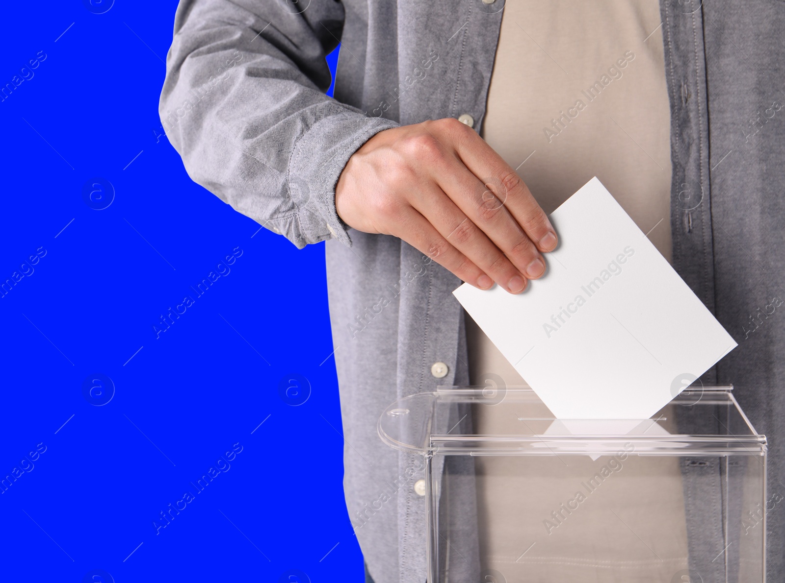 Image of Man putting his vote into ballot box on blue background, closeup