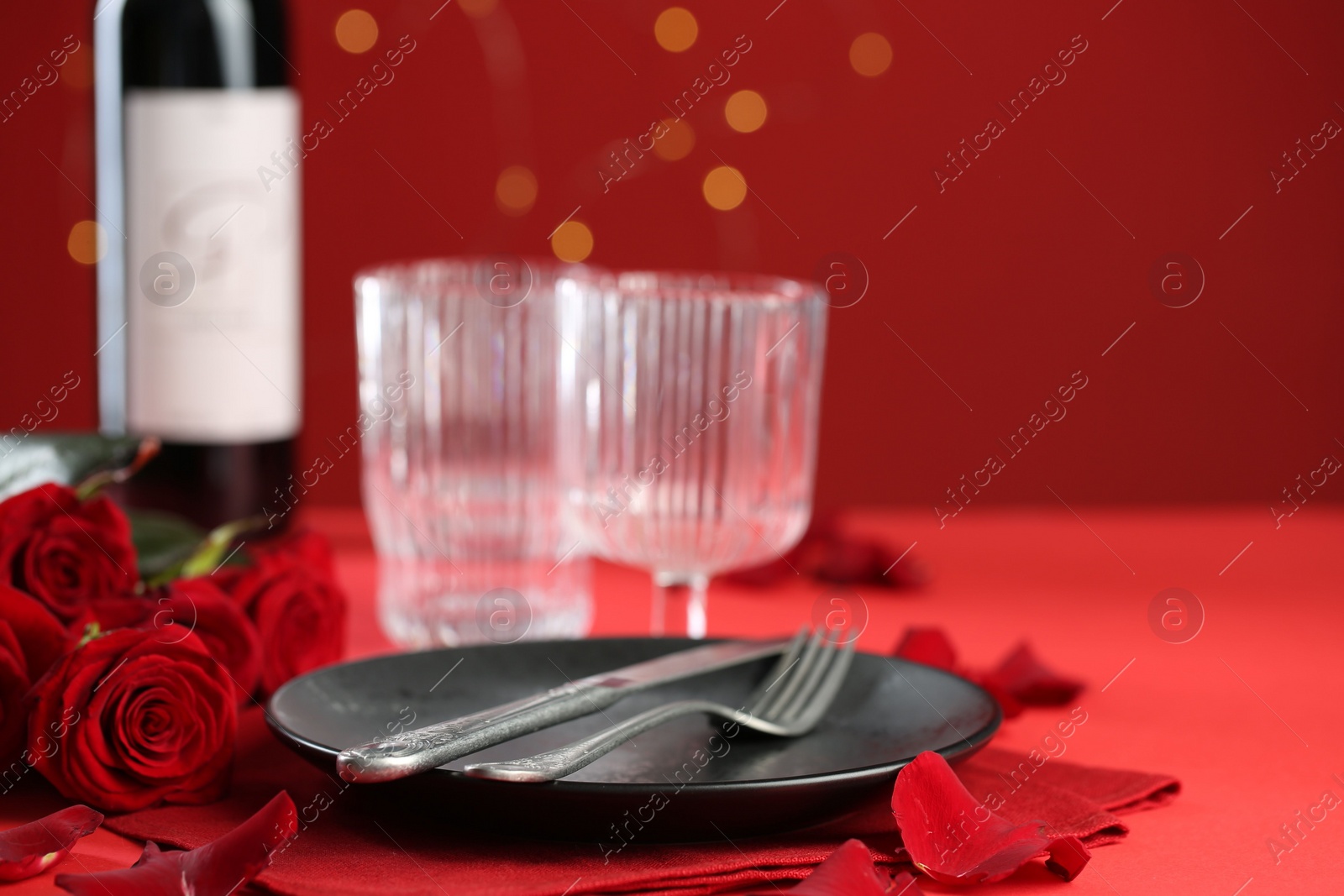 Photo of Place setting with roses for romantic dinner on red table, closeup. Space for text