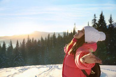 Happy young woman outdoors on snowy winter day. Space for text