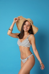 Pretty sexy woman with slim body in stylish striped bikini on blue background