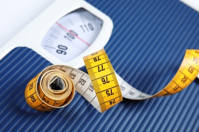 Photo of Scales with tape measure, closeup view. Diet and weight loss