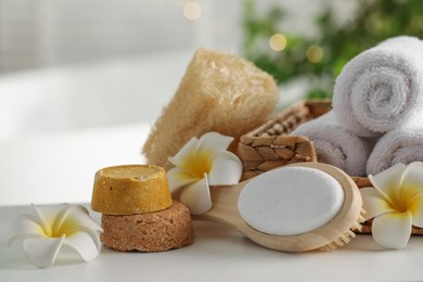 Composition with different spa products and plumeria flowers on white table indoors, closeup