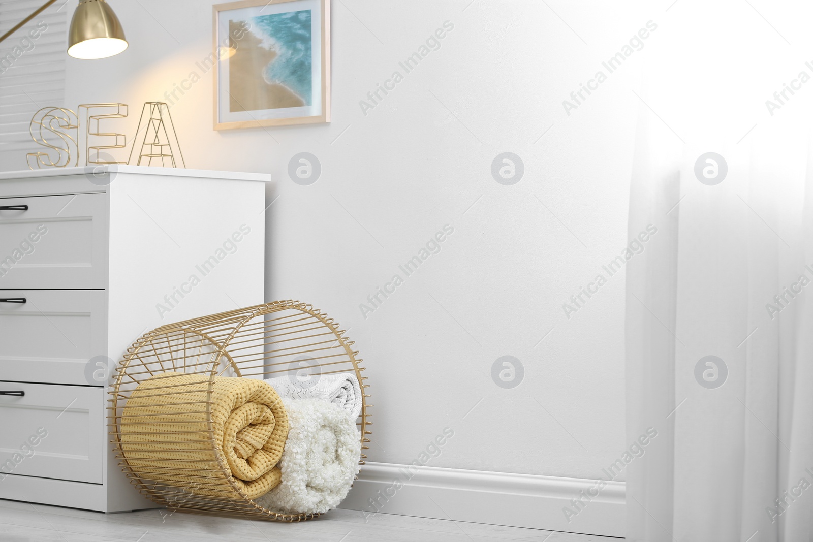 Photo of Basket with soft plaid near commode in room. Space for text