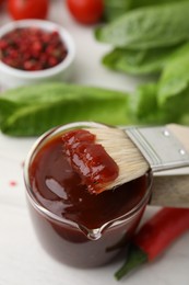 Photo of Marinade and basting brush on white table, closeup