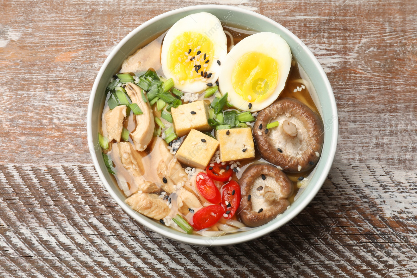 Photo of Bowl of delicious ramen on wooden table, top view. Noodle soup