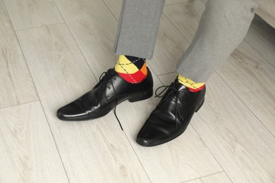 Photo of Man wearing stylish shoes and colorful socks indoors, closeup