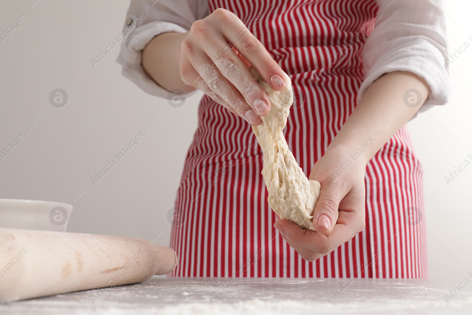 Photo of Woman with fresh dough at table, closeup. Cooking grissini