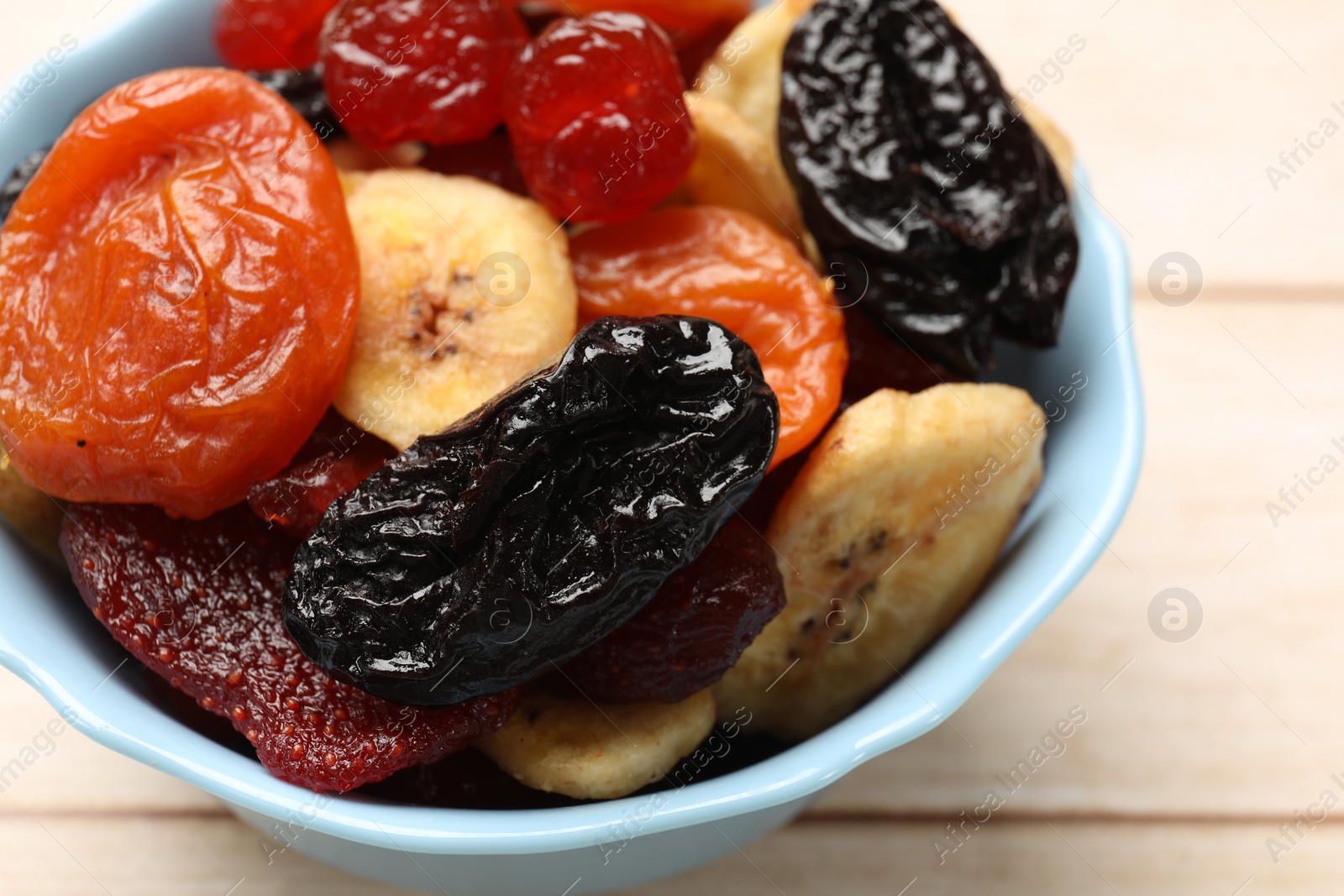 Photo of Mix of delicious dried fruits on white wooden table, closeup