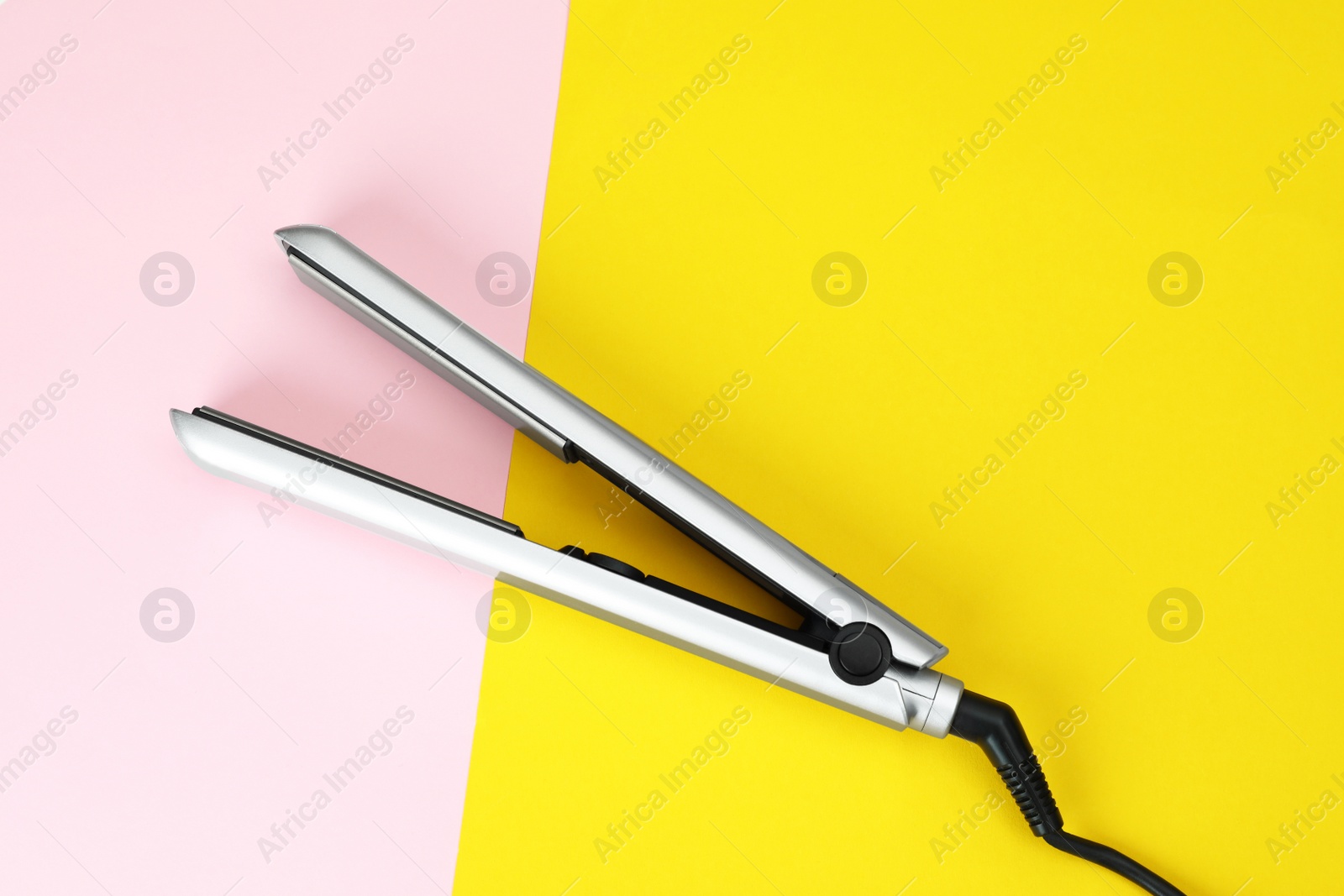 Photo of Modern hair iron for straightening on color background, top view