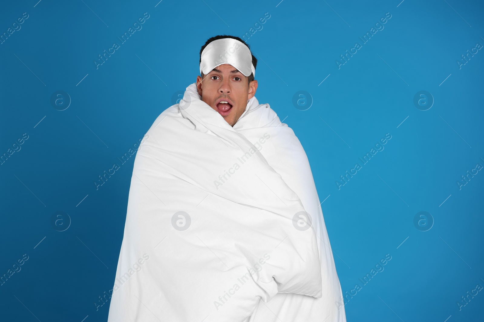 Photo of Man wrapped in blanket on blue background