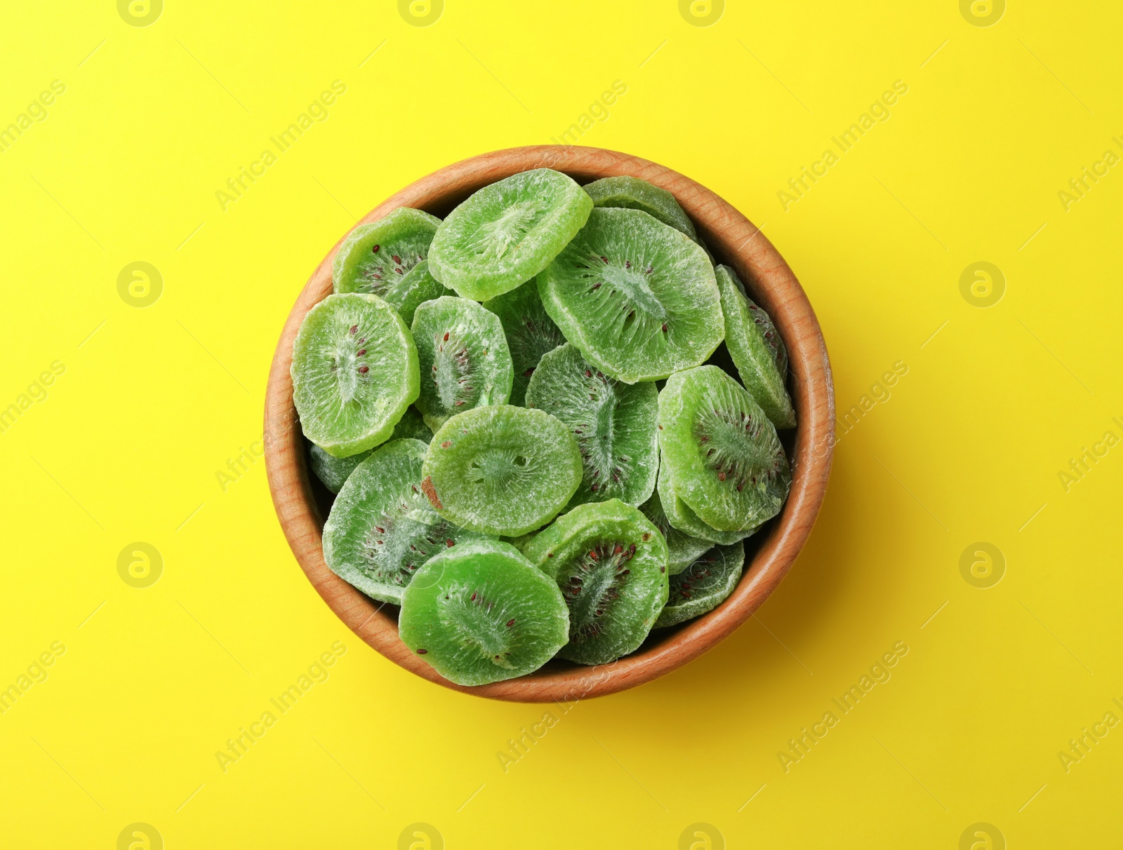 Photo of Bowl with slices of kiwi on color background, top view. Dried fruit as healthy food