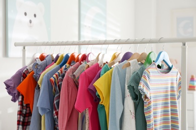 Photo of Different child's clothes hanging on rack in room