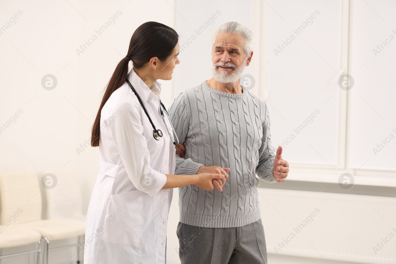 Photo of Smiling nurse supporting elderly patient in hospital