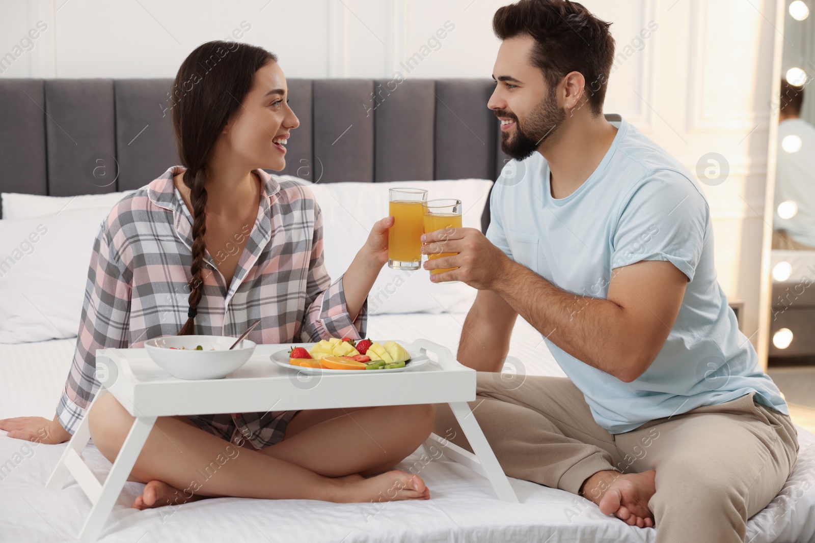 Photo of Happy couple having breakfast on bed at home