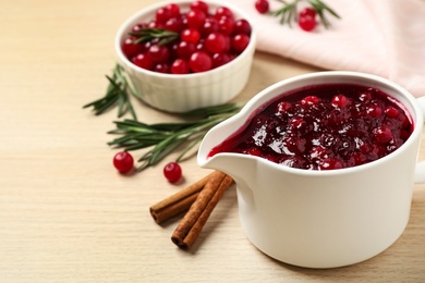 Cranberry sauce in pitcher on wooden table