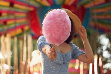 Stylish young woman holding cotton candy at funfair